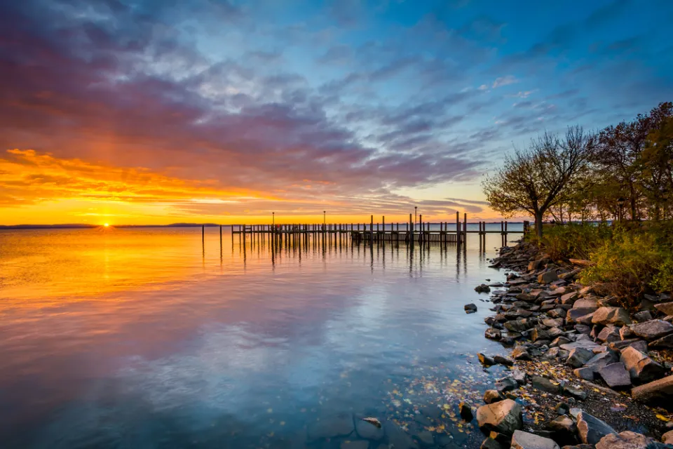 Colorful sunset viewed from rockly shoreline on Chesapeake Bay with dock in distance